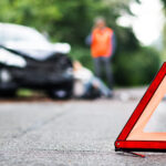 A hazard road marker with an car accident in the background